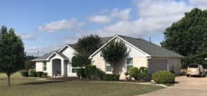 A suburban house with a well-kept lawn and trees.