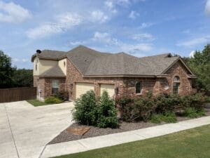 A single-story brick house with a well-kept lawn under a blue sky.