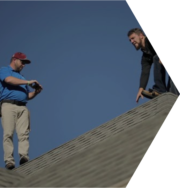 Two men working on a rooftop under a clear blue sky.