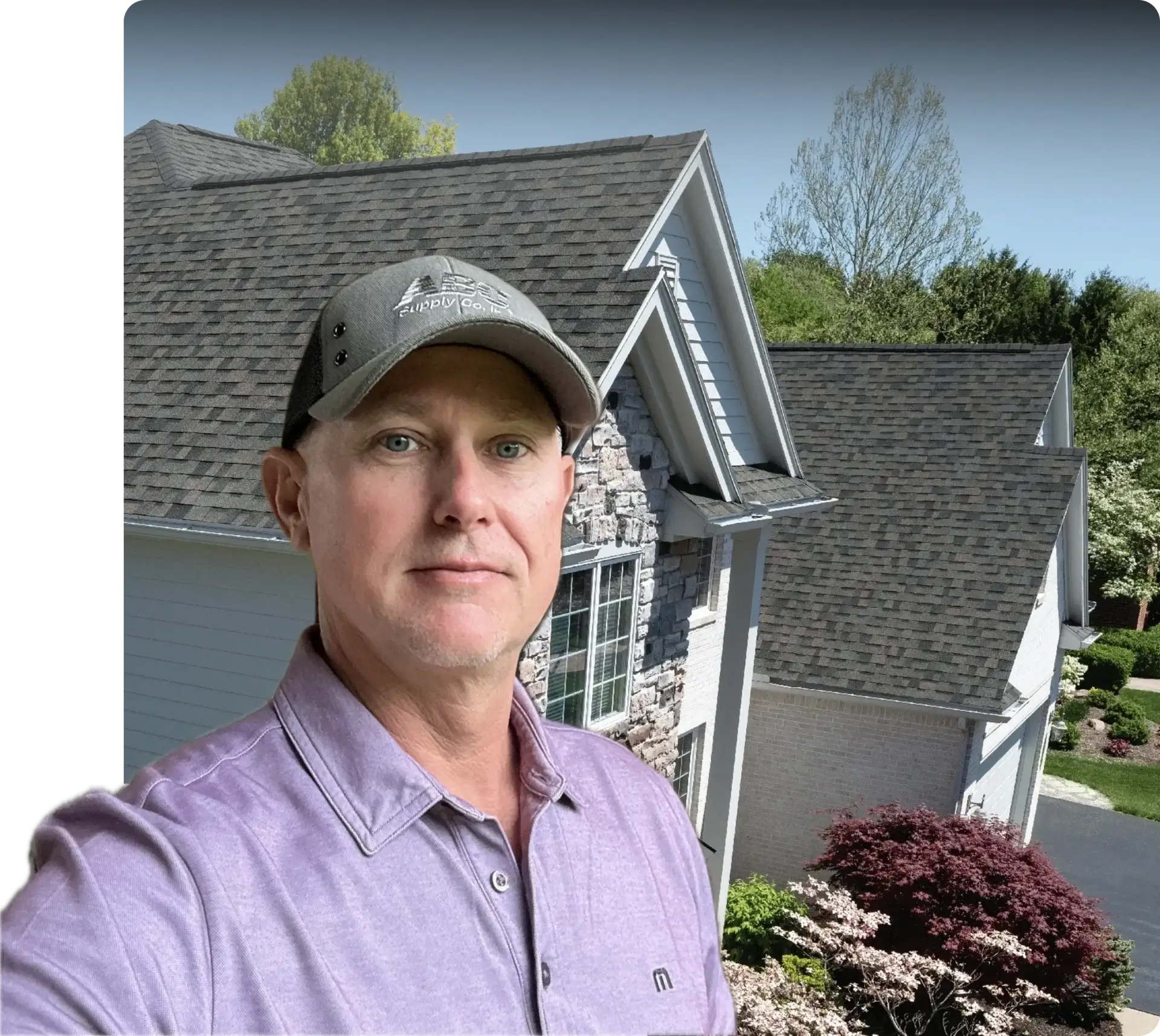A man wearing a gray cap and purple shirt outdoors near houses.